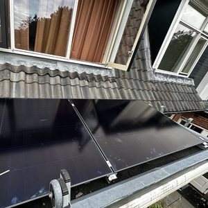 De afbeelding toont een installatie van zonnepanelen op een dak, met een close-up van de panelen en een gereedschap in gebruik.