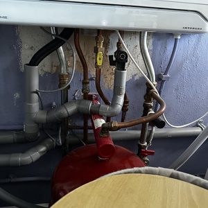 Een installatie van een airconditioningsysteem met leidingen en een expansievat zichtbaar. Het systeem lijkt recentelijk geïnstalleerd en is klaar voor gebruik.