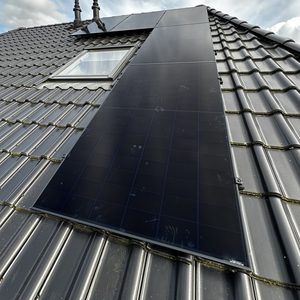 Een installatie van zonnepanelen op een schuin dak, met een helder zicht op de panelen en het dakmateriaal op de achtergrond.