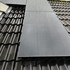 Installatie van zonnepanelen op een hellend dak, zichtbaar met regendruppels op het oppervlak.