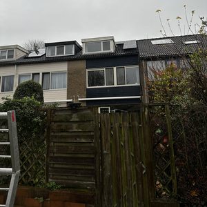 De foto toont zonnepanelen gemonteerd op het dak van een woning, zichtbaar onder een grijze lucht.