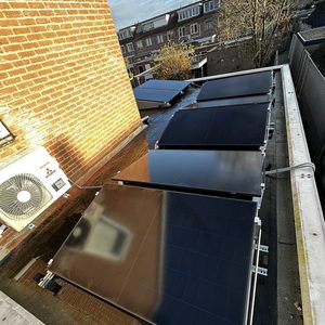 De foto toont een installatie van zonnepanelen op een plat dak met een uitzicht op de omliggende gebouwen.