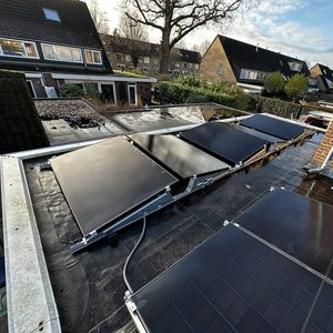 De afbeelding toont een installatie van zonnepanelen op een plat dak, met meerdere panelen in een rijenconfiguratie.