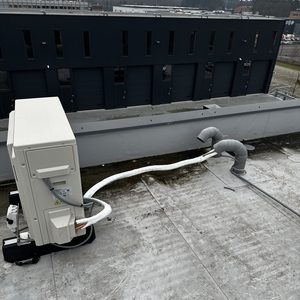 De foto toont een airconditioning-installatie op een rooftop met aangesloten leidingen voor koeling en ventilatie.