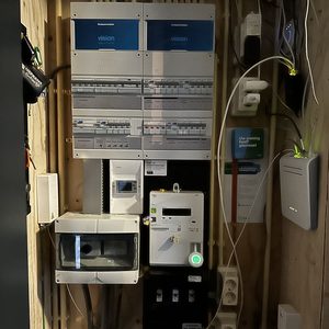 De afbeelding toont een installatie van een thuisbatterij, compleet met een meterkast en diverse aansluitingen voor energiebeheer.