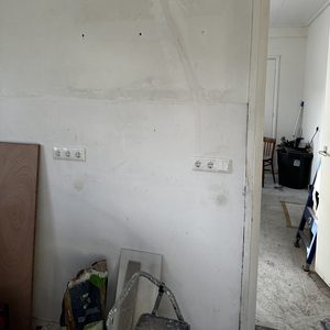 De foto toont een muur met een meterkast en enkele elektriciteitsvoorzieningen in een onvoltooide ruimte.