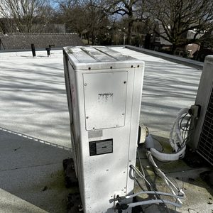Een airco-installatie geplaatst op een plat dak, zichtbaar met aansluitingen en omgevingsdetails.