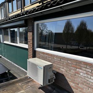 Een buitenunit van een airconditioningsysteem aan de muur bevestigd, die koude lucht levert en efficiëntie voor binnenruimtes bevordert.
