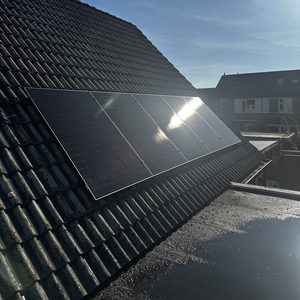 Deze installatie toont zonnepanelen op een hellend dak, met een heldere lucht op de achtergrond.