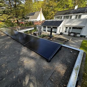 Een gedeelte van een zonnepaneleninstallatie op een plat dak, met meerdere zonnepanelen zichtbaar in een rechte lijn.