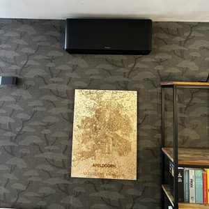 Een wandmontage airconditioningseenheid geïnstalleerd op een muur, gecombineerd met decoratieve elementen in de kamer.