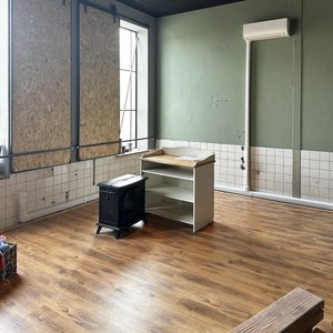 Het beeld toont een geïnstalleerde airconditioner in een ruimte met een houten vloer en een bureau.