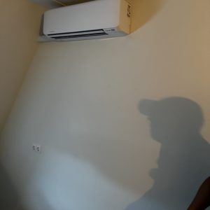 Een wandairco-installatie die hangt aan een muur, bereidt de ruimte voor op een comfortabele temperatuur.